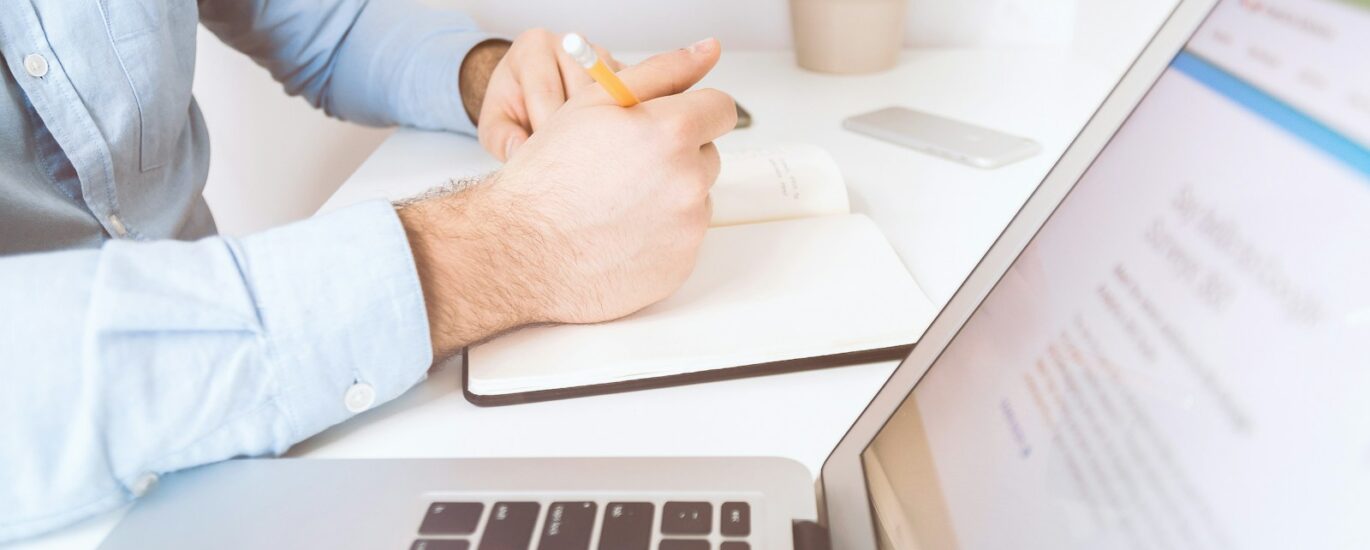 person writing on white notebook